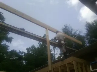 Carpenter setting a ridge beam over a new addition frame — Ice Dam Removal by Roofing Brothers in Belmond