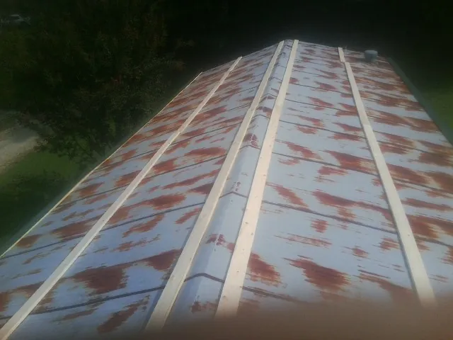 Rusted metal roof panels with new wood purlins before replacement — Storm Damage Roof Repair in Belmond by Roofing Brothers