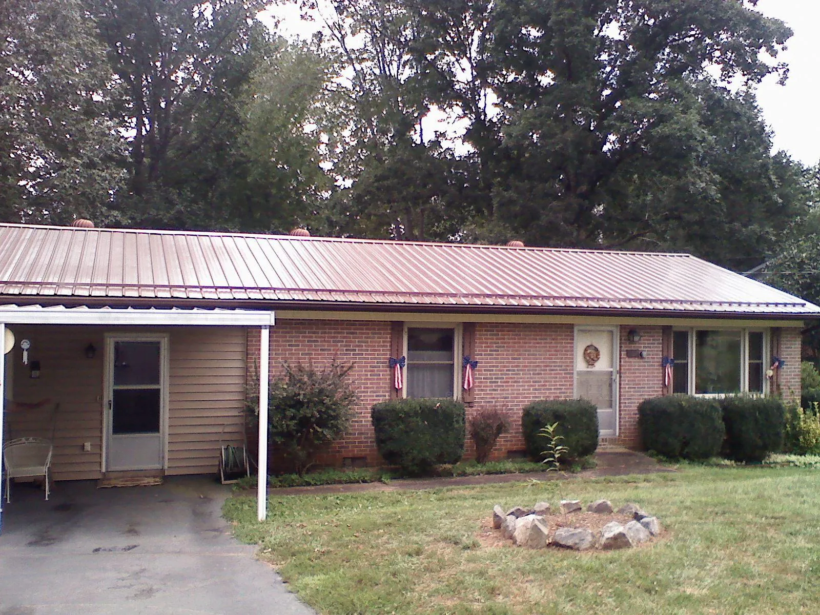 Bronze metal roof and carport on a brick ranch home — Roof Repair work by our crew in Belmond